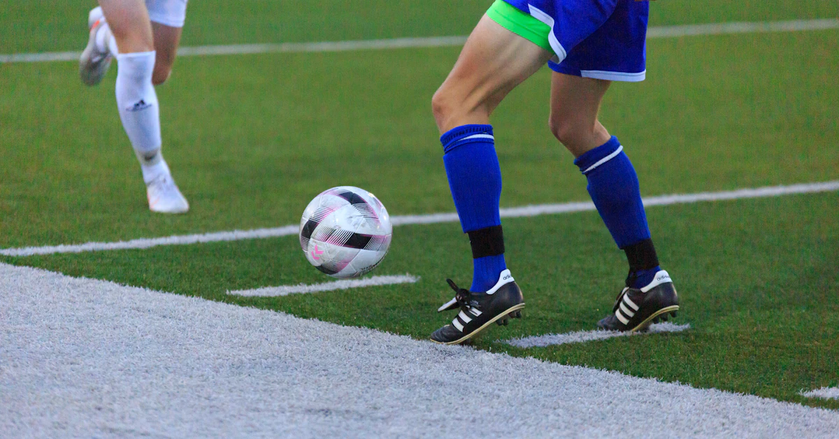 person in blue and white soccer jersey kicking soccer ball on field during daytime