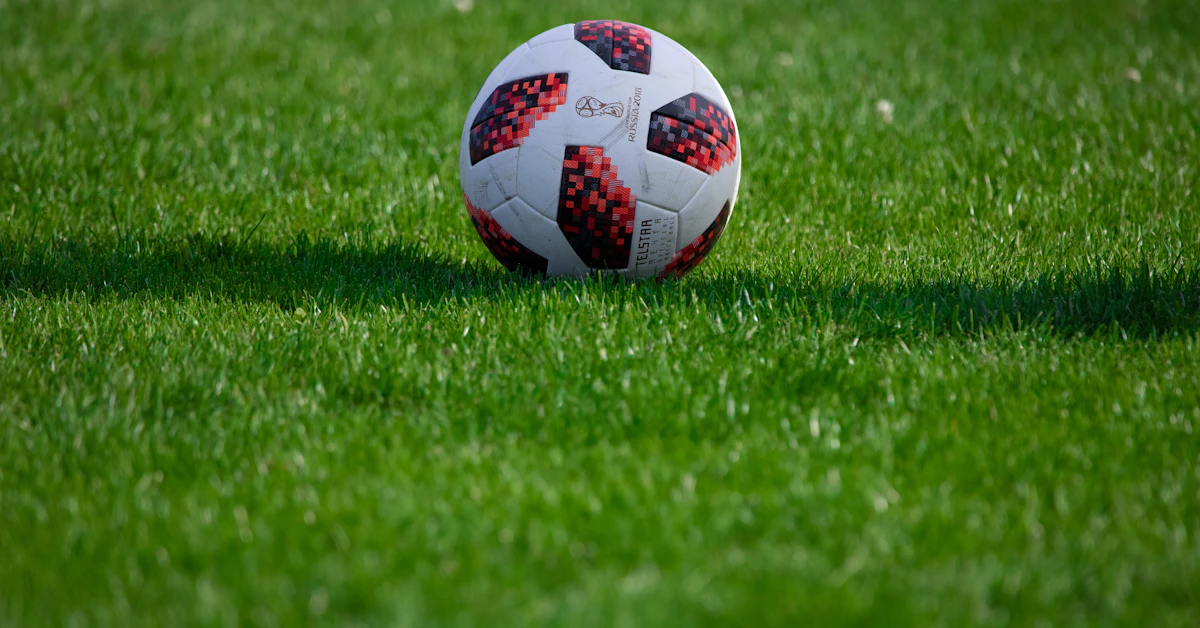 white and red soccer ball on green grass field during daytime